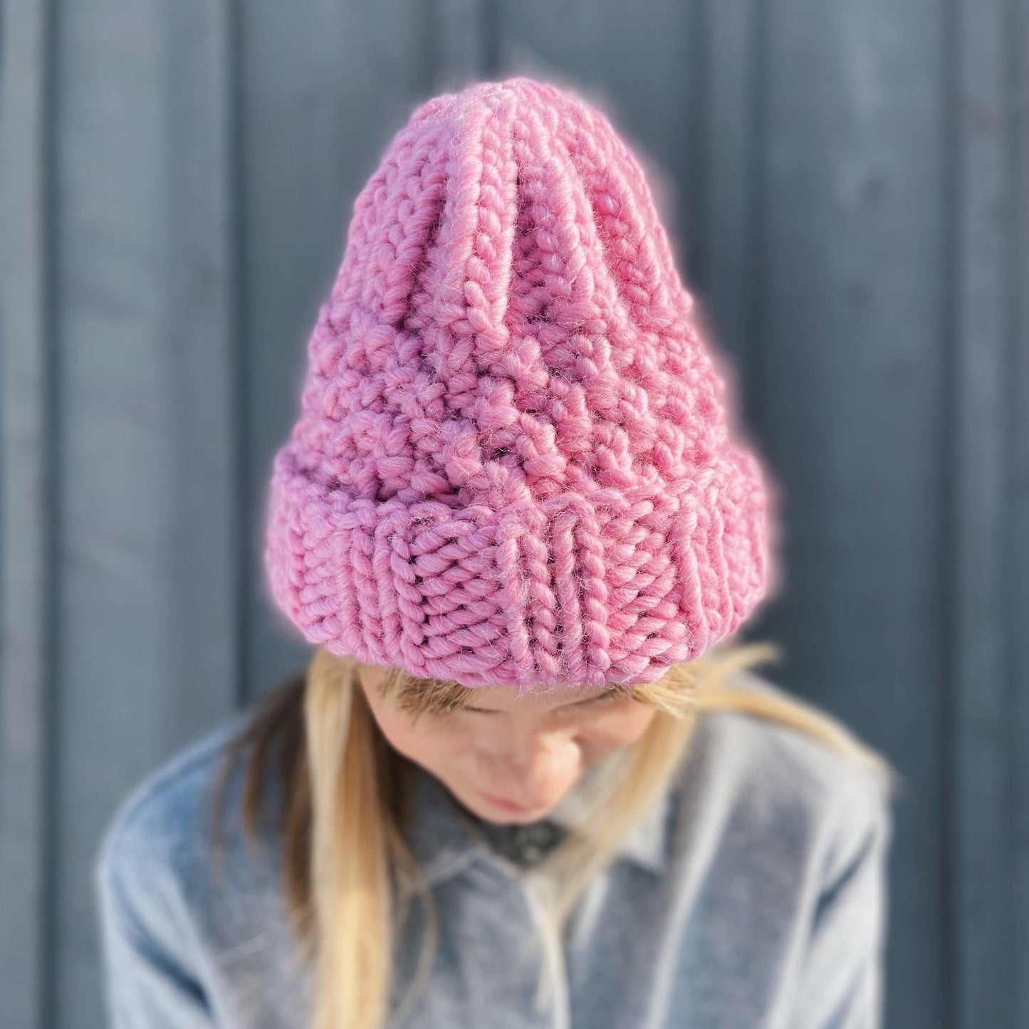 close up of a pink, Ruka knitted beanie worn by a woman outdoors